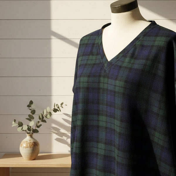 Mannequin wearing a black watch tartan nightshirt against a white wall.
