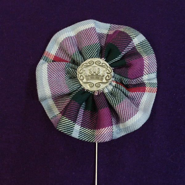 Plaid brooch with a central emblem on a purple background