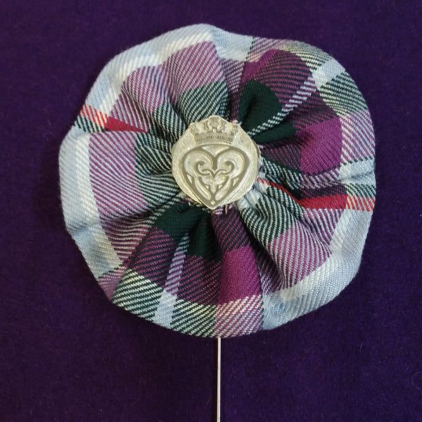 Plaid fabric flower brooch with a central emblem on a purple background